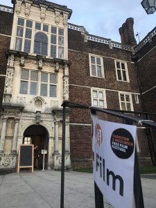 The front of Charlton House at dusk in the background with a poster advertising a free film screening at the front.