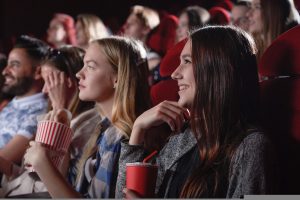 Young women in a cinema enjoying a film, with drinks and popcorn